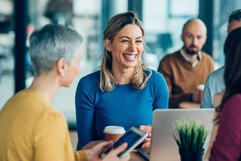 A woman with hearing loss laughing in a business setting. 